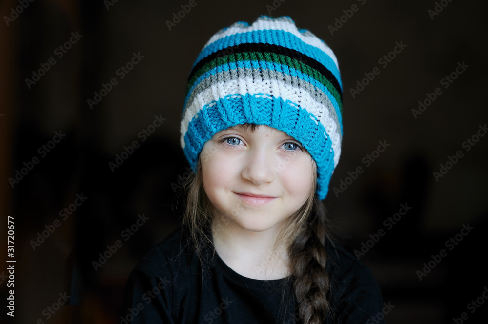 Portrait of cute little girl in stripe hat on dark background Portrait of cute little girl in stripe hat on dark background