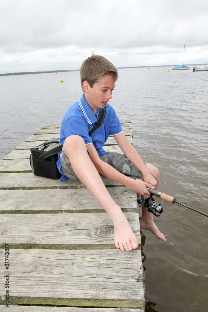 Kid sitting on a pontoon with fishing rod Kid sitting on a pontoon with fishing rod