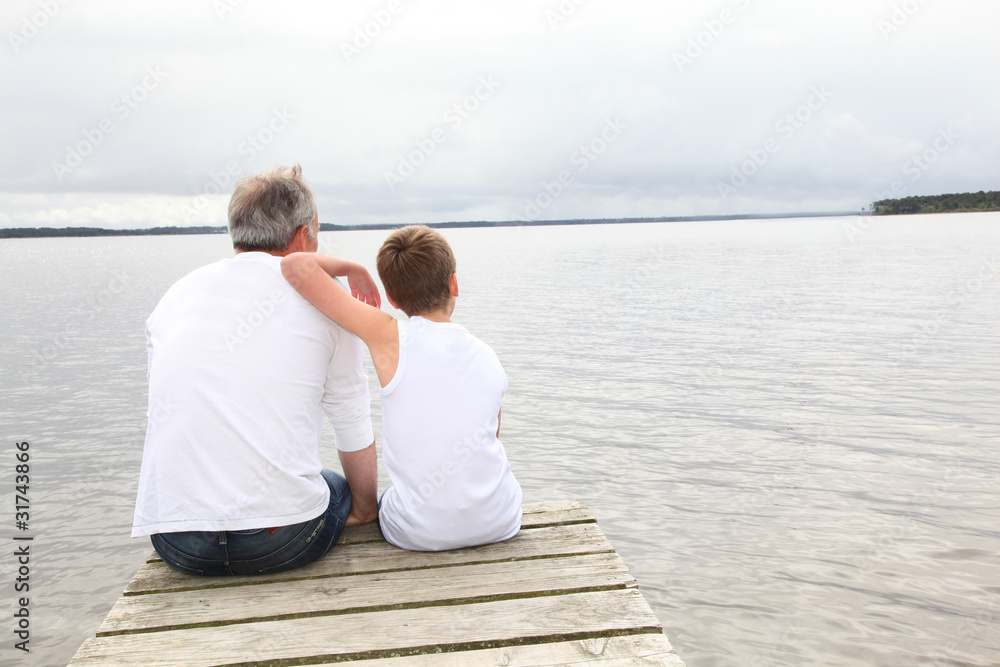 Portrait of father and son sitting on a pontoon Portrait of father and son sitting on a pontoon