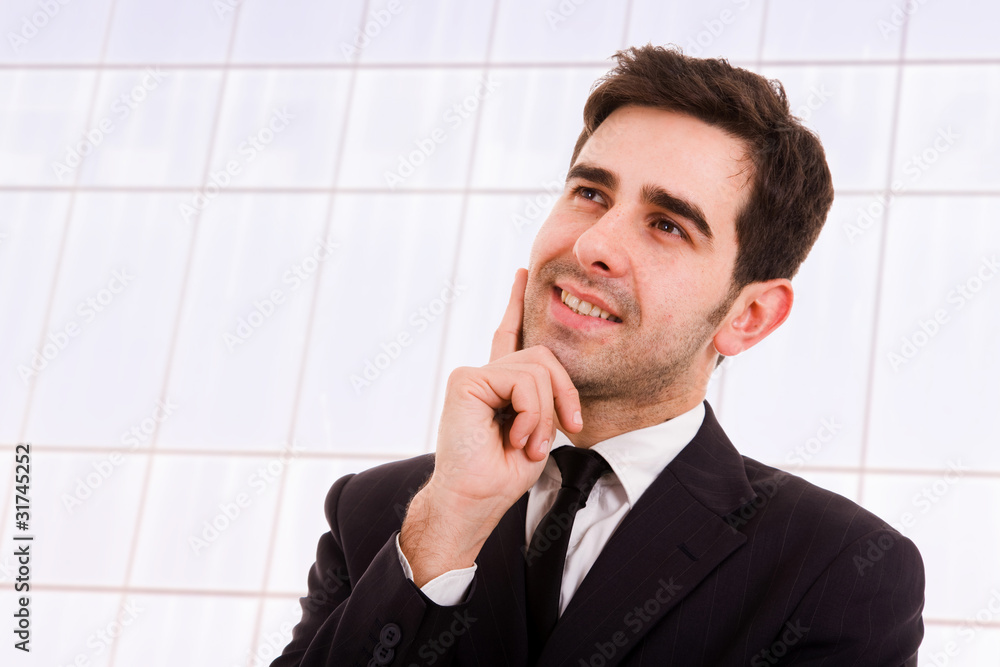 Closeup of a pensive smiling young business man standing at a mo Closeup of a pensive smiling young business man standing at a mo