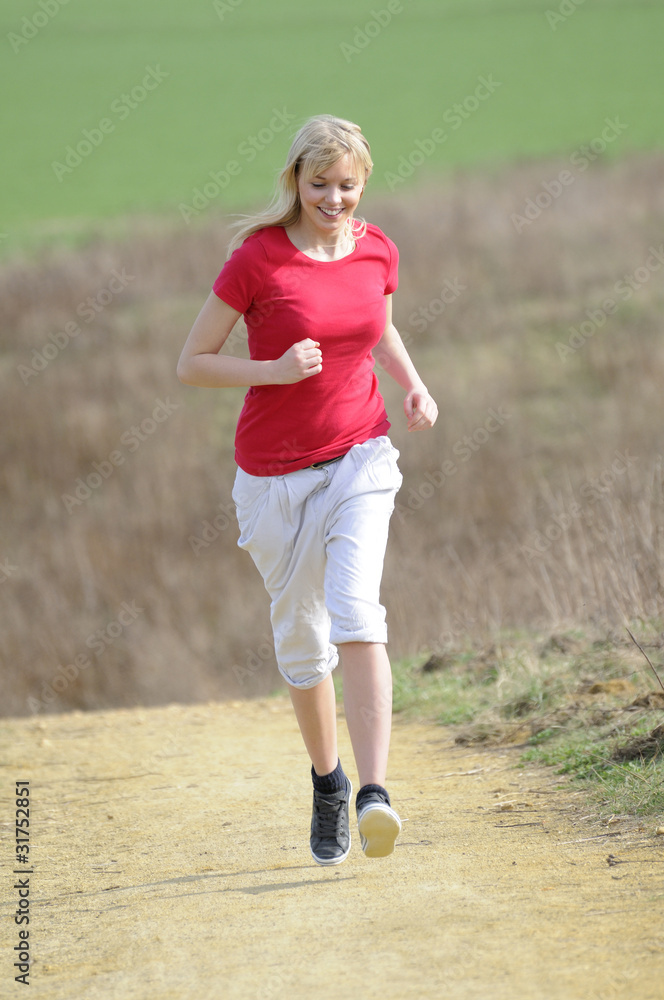 junge frau beim joggen auf einem feldweg junge frau beim joggen auf einem feldweg