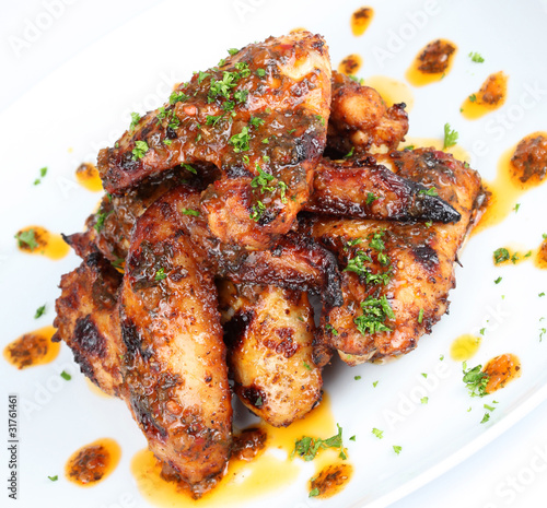 Hot grilled chicken wings on white plate with drizzle of sauce