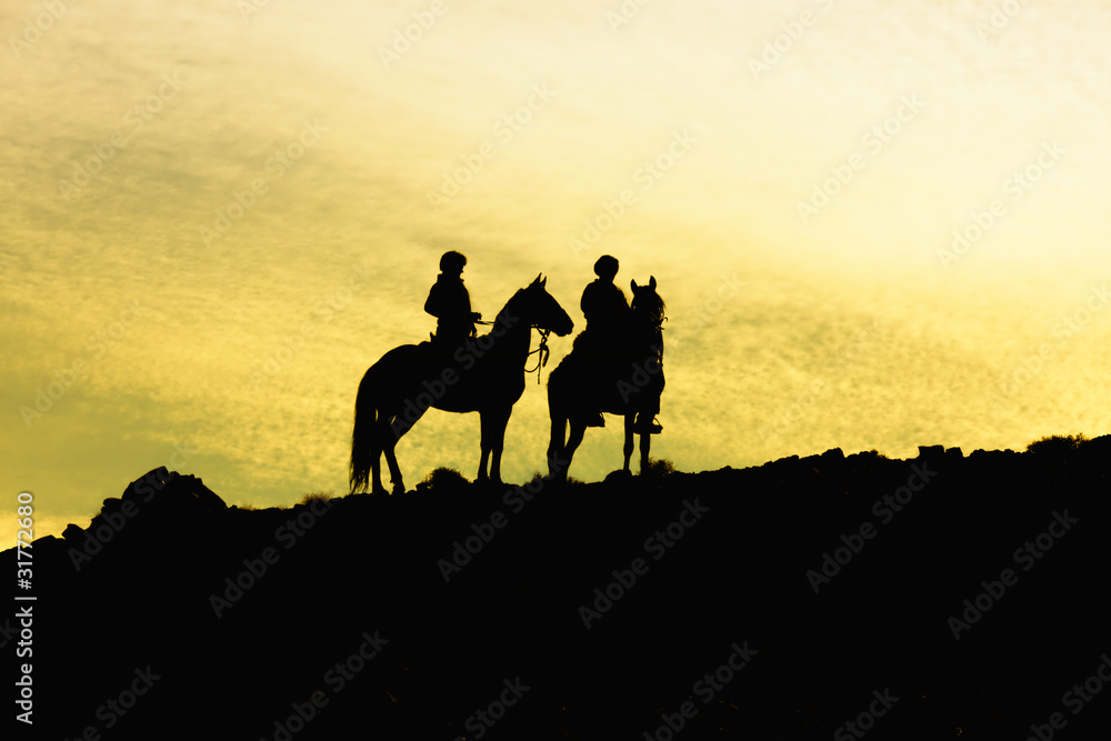 Silhouette of two horses with riders