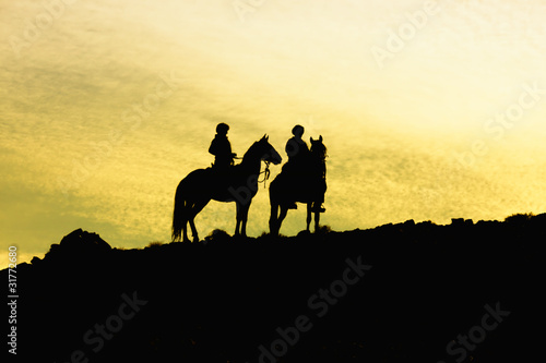 Silhouette of two horses with riders