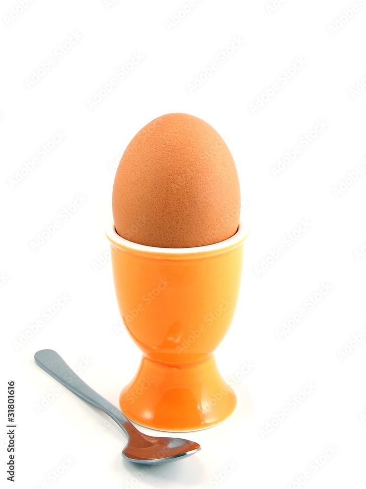 A boiled egg in cup with spoon on white background A boiled egg in cup with spoon on white background