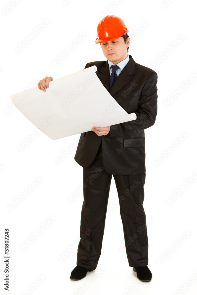 Concentrated businessman with helmet analyzing building projects Concentrated businessman with helmet analyzing building projects
