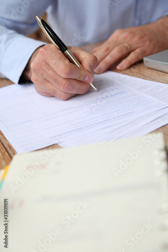 Closeup of senior man filling in tax form
