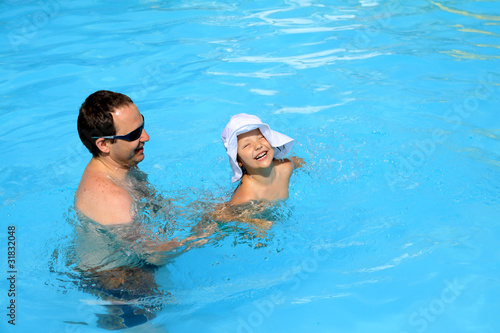 Dad teaches his daughter to swim in the pool