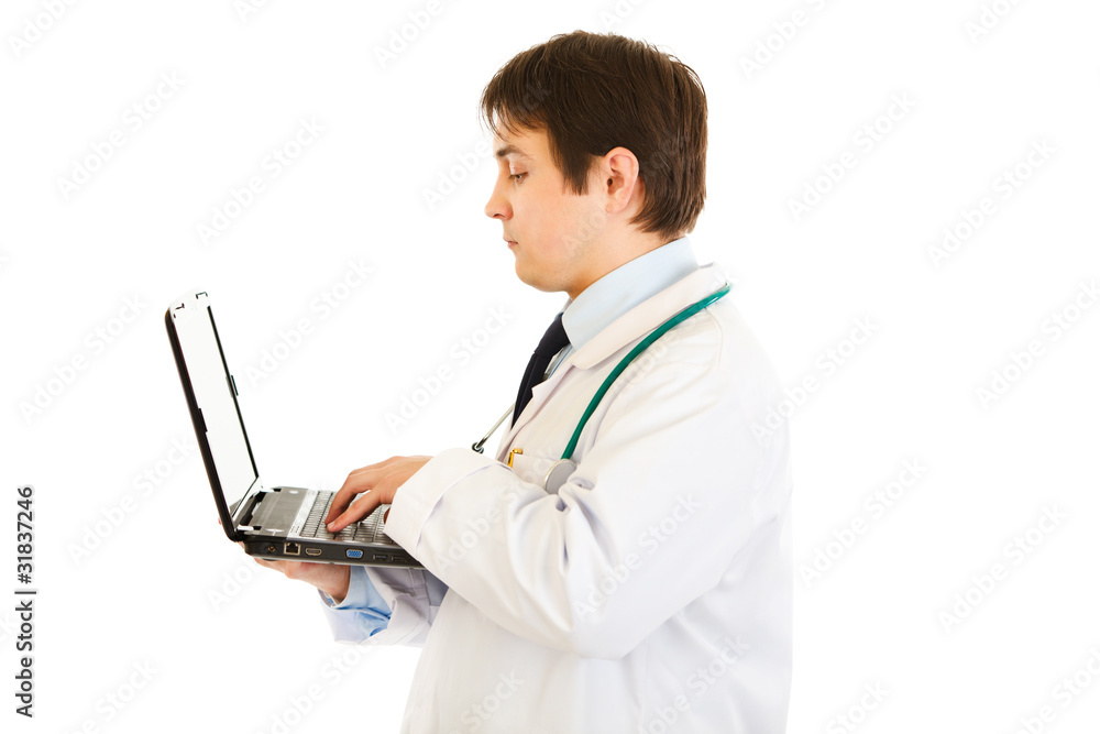 Serious medical doctor  working on laptop isolated on white.