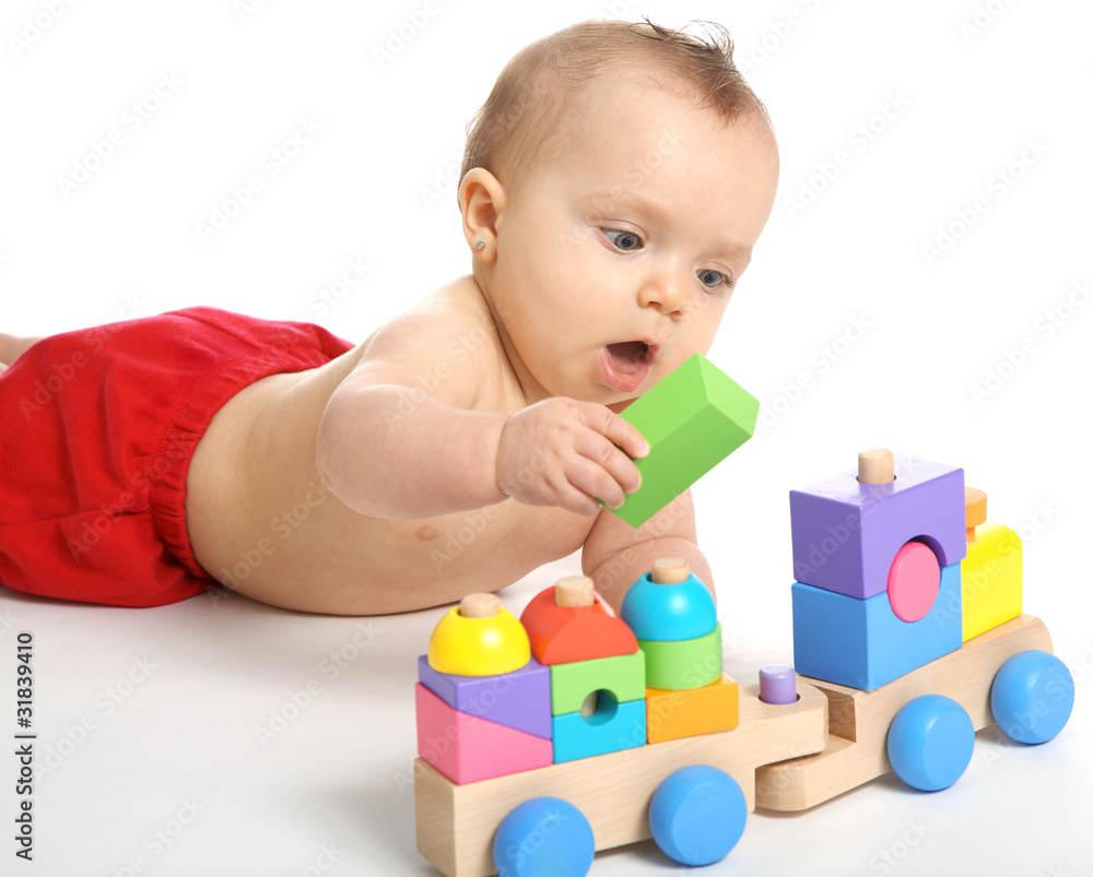 Baby girl playing with an wooden train toy Baby girl playing with an wooden train toy