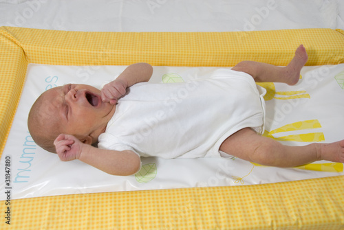 Newborn Baby Boy Aged 9 Days Lying on Changing Mat Crying photo