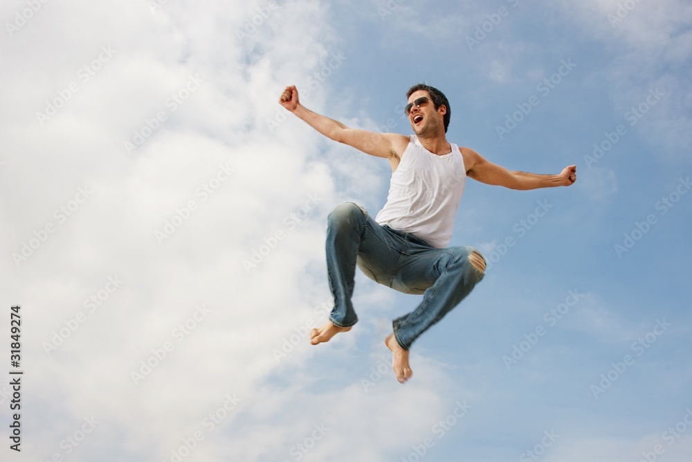 Happy young man jumping against blue sky
