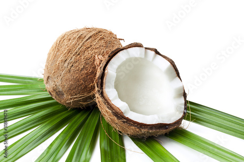 Ganze und halbe Kokosnuss auf Palmblatt isoliert