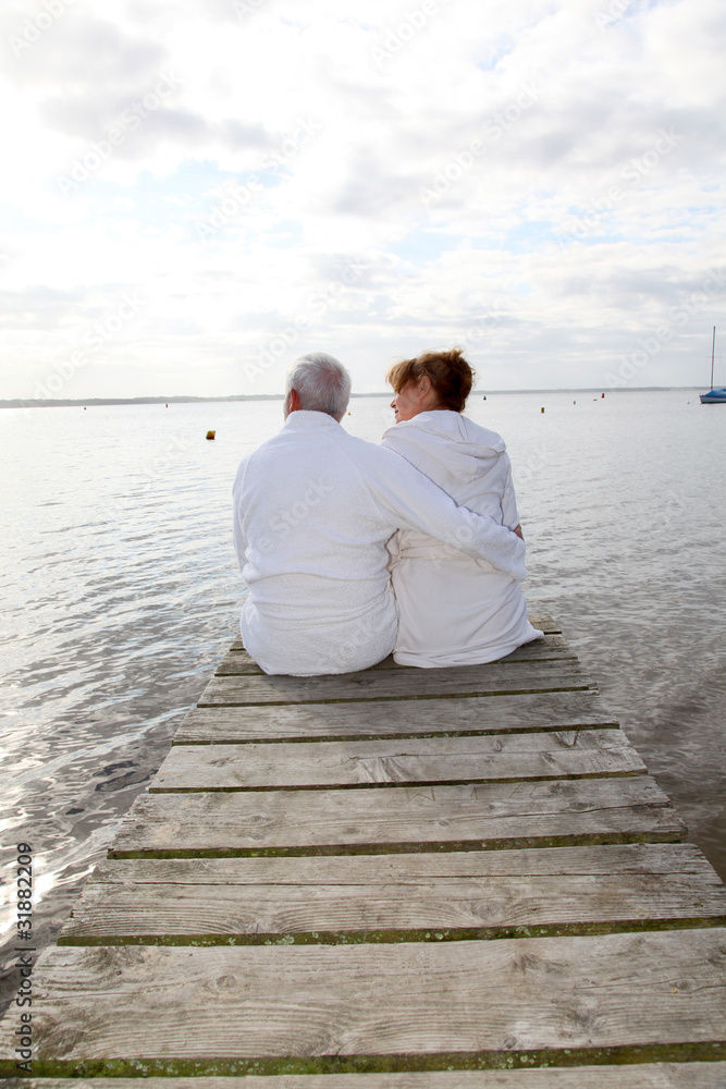 Senior couple in bathrobe sitting on a pontoon