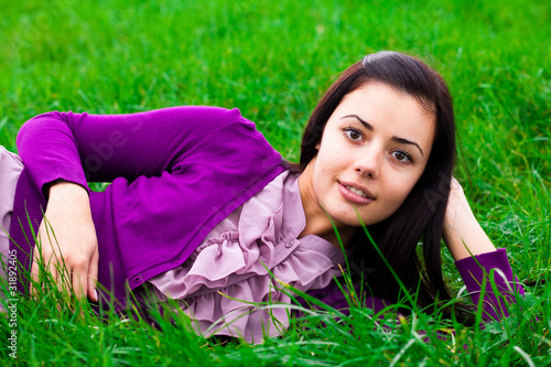 beautiful young woman lying on green grass