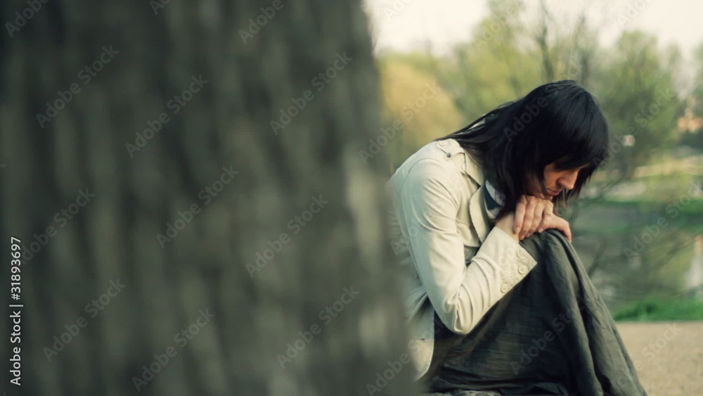 Pensive woman sitting in the park, dolly shot Pensive woman sitting in the park, dolly shot