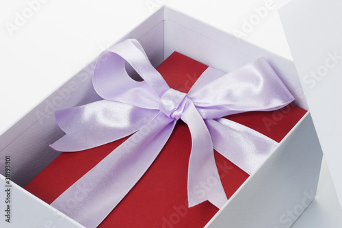 Red giftbox with bow ribbon inside open white box