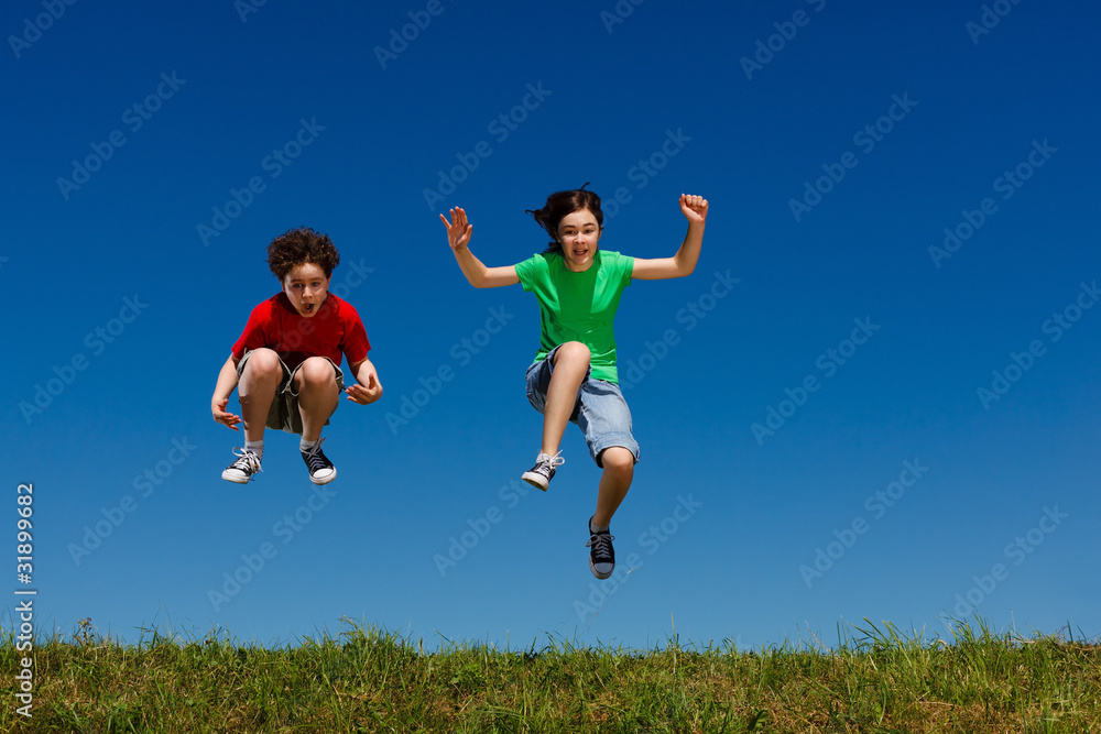 Girl and boy jumping, running against blue sky Girl and boy jumping, running against blue sky