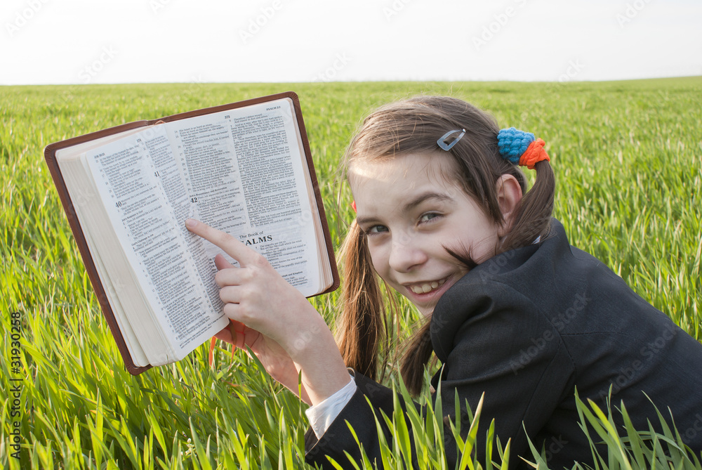Girl with the Bible laying on the grass