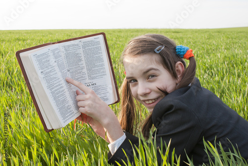 Obraz na płótnie Girl with the Bible laying on the grass w salonie