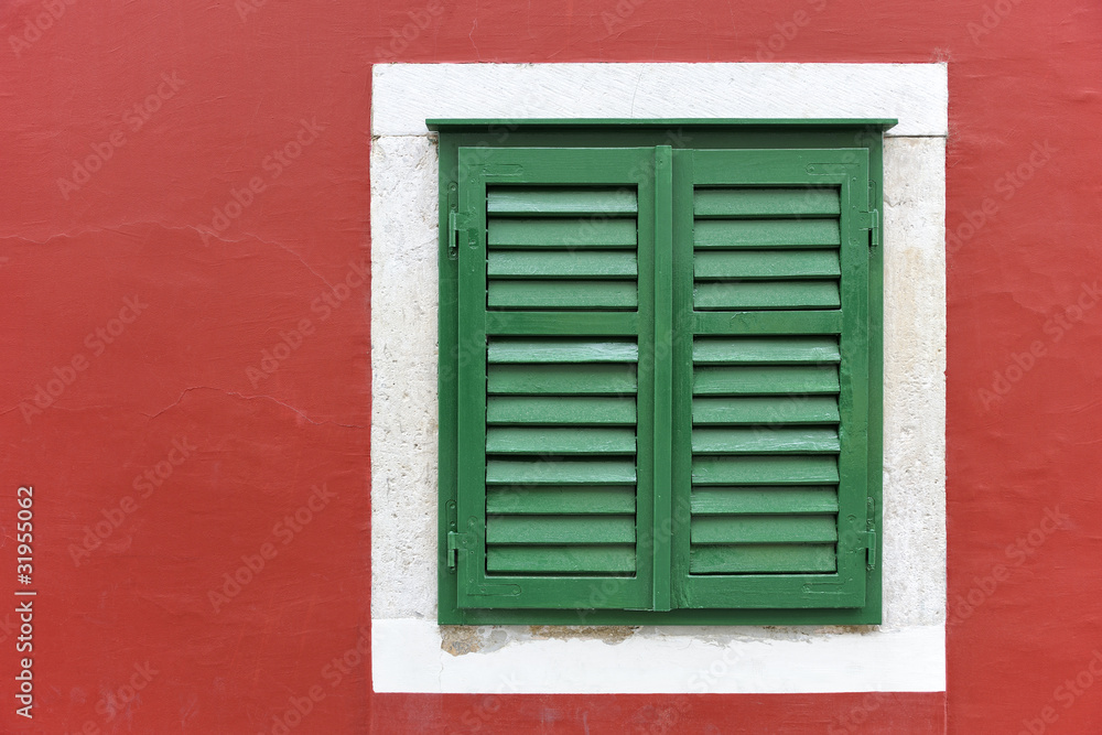 Single window with green shutters set in red wall in Skradin