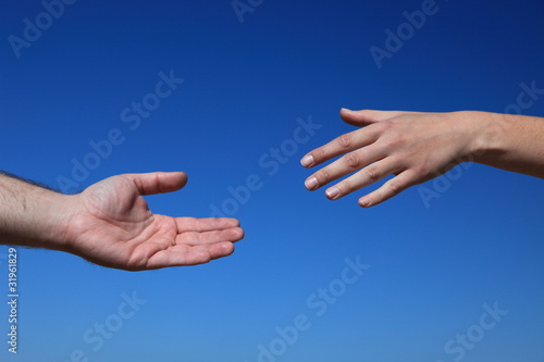 Zwei Personen reichen sich die Hand vor blauem Himmel © Kaesler Media