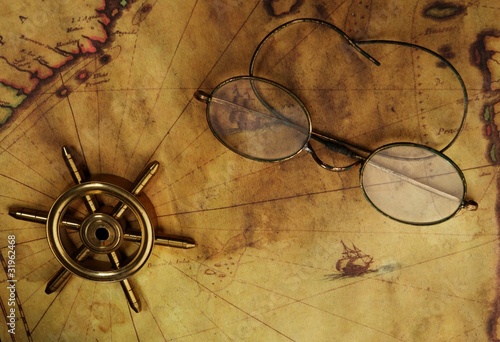 Glasses and sea wheel on the old map photo