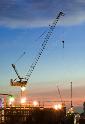 Derrick cranes at construction site at sunset time
