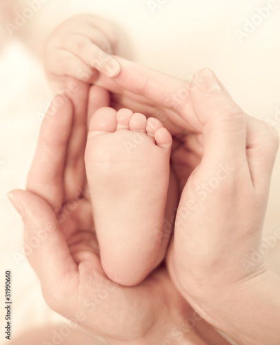 Mother's hands carefully keep baby's foot with tenderness