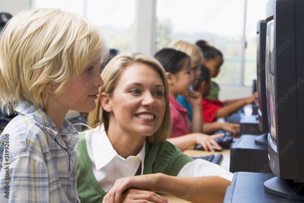 Teacher helping kindergarten children learn how to use computers Teacher helping kindergarten children learn how to use computers