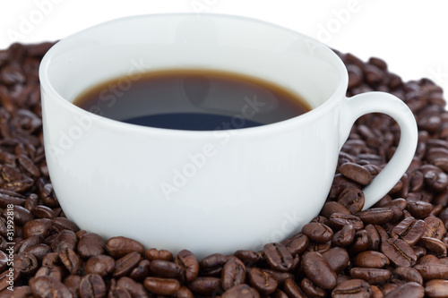 White cup of coffee surrounded with coffee beans
