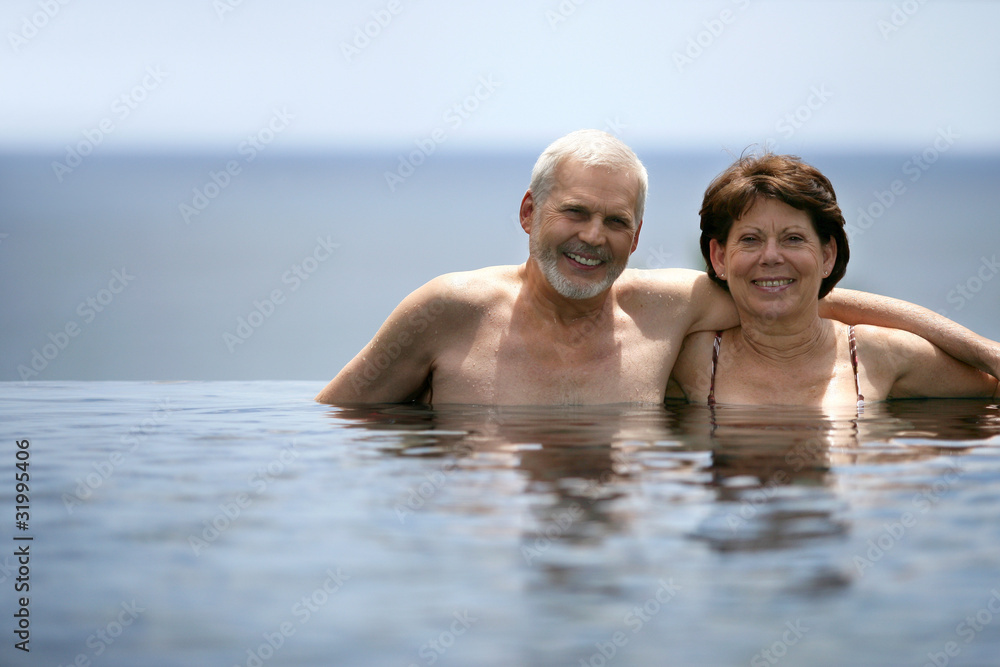 Senior couple bathing in swimming pool Senior couple bathing in swimming pool