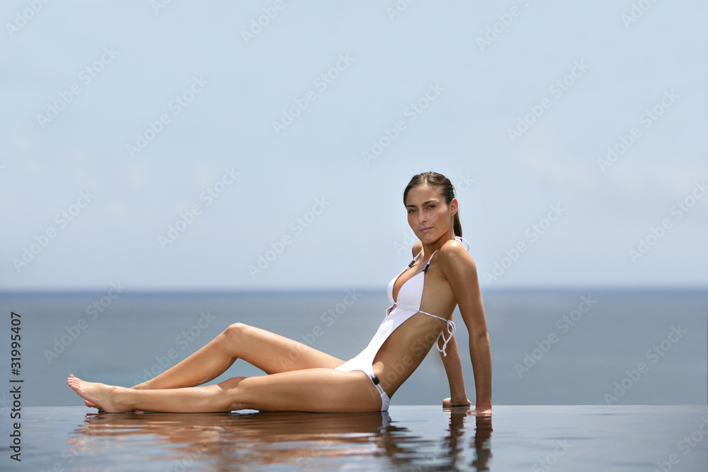 Young woman in swimsuit laid at a poolside Young woman in swimsuit laid at a poolside