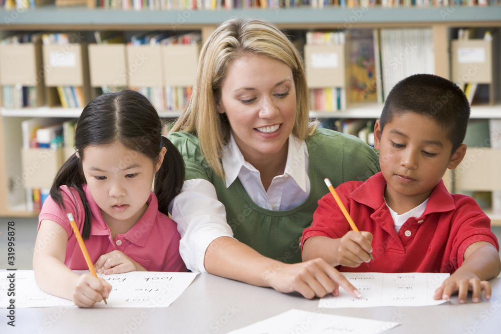 Kindergarten teacher helping students with writing skills Kindergarten teacher helping students with writing skills