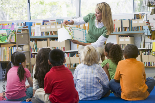 Kindergarten teacher reading to children in library