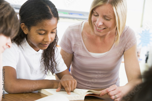 A schoolgirl and her teacher reading a book in class photo