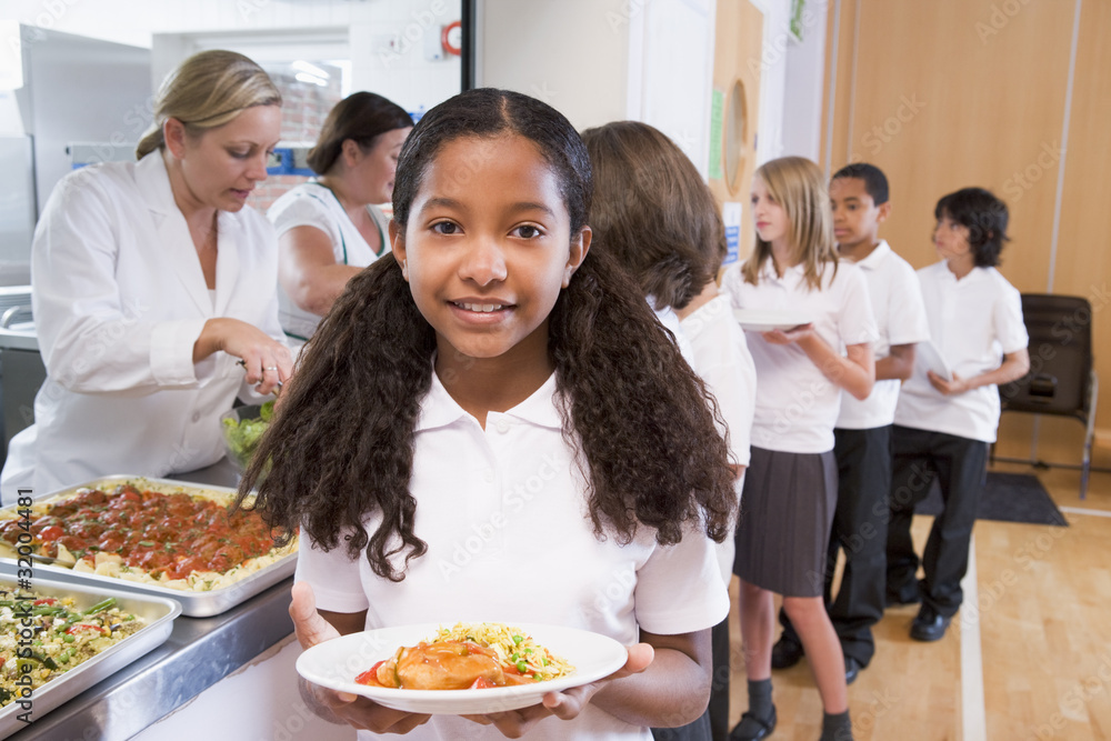 Schoolgirl holding plate of lunch in school cafeteria Schoolgirl holding plate of lunch in school cafeteria