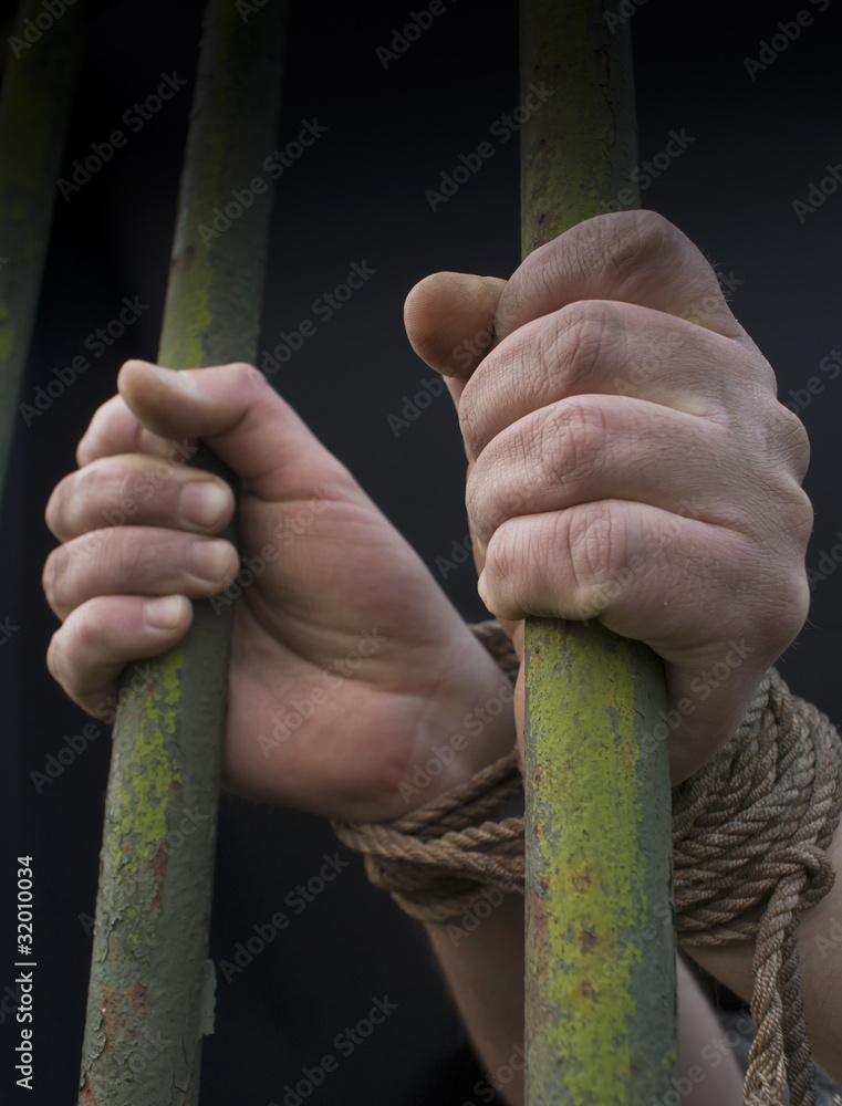 Hands behind the bars tied with rope
