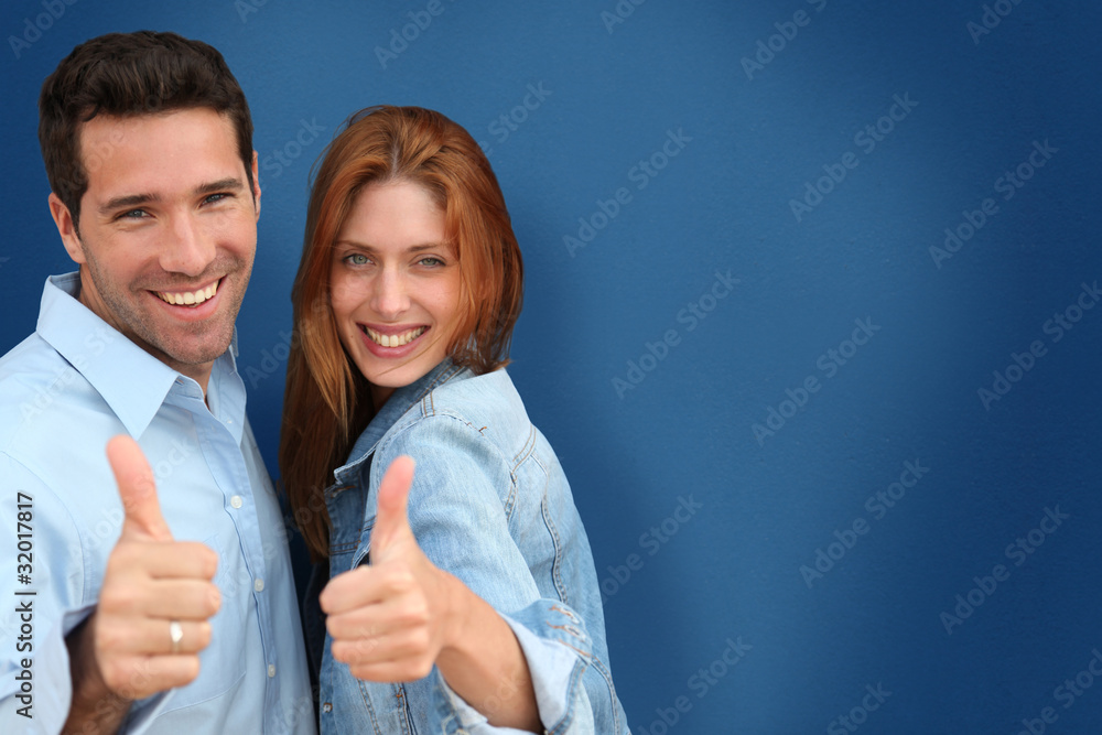 Couple showing thumbs up on blue background Couple showing thumbs up on blue background