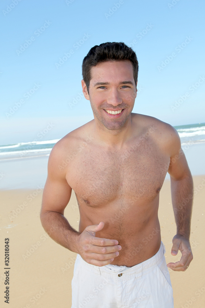 Smiling man jogging on a sandy beach