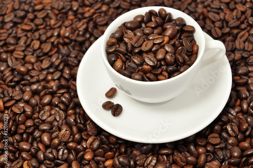 Cup with coffee beans on coffee background