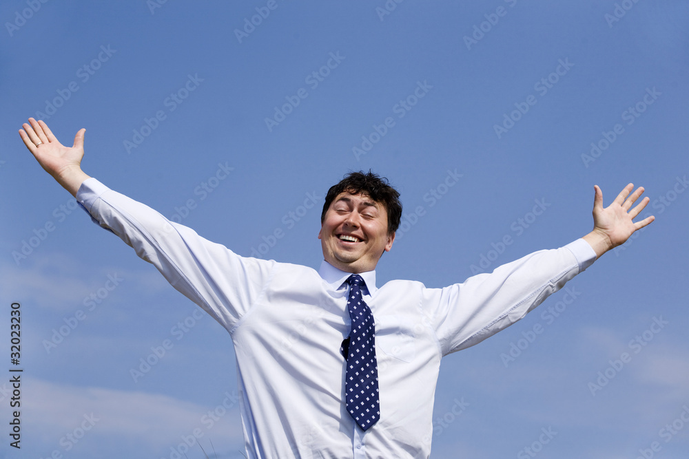 Mid adult business man with arms outstretched against blue sky Mid adult business man with arms outstretched against blue sky