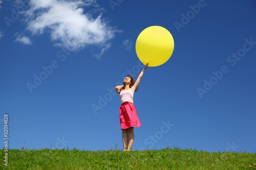 Woman stands in summer in field holds balloon and looks in sky