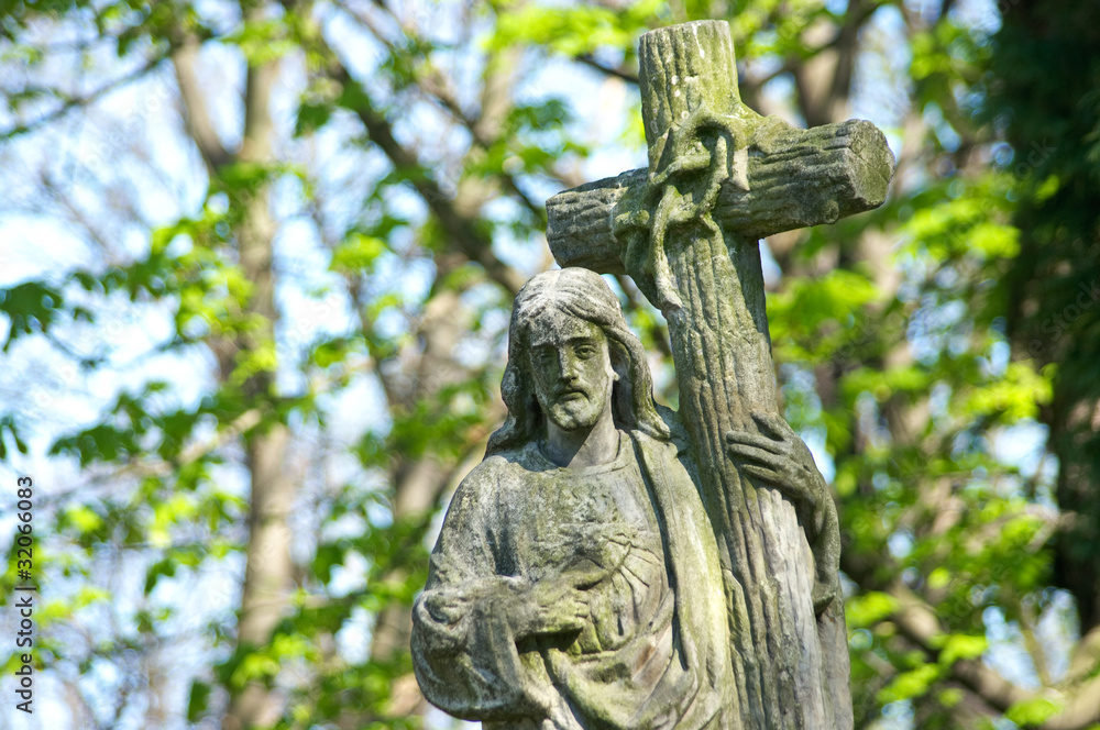 Very old stone Christ statue on tomb in graveyard