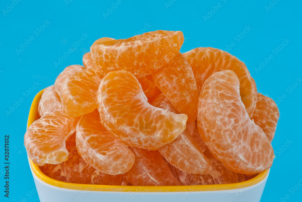 peeled oranges in a cup on blue background peeled oranges in a cup on blue background