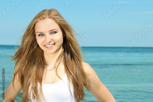 Portrait of a beautiful smiling young lady on the beach backgrou