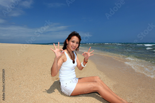 波打ち際で日光浴を楽しむ笑顔の女性