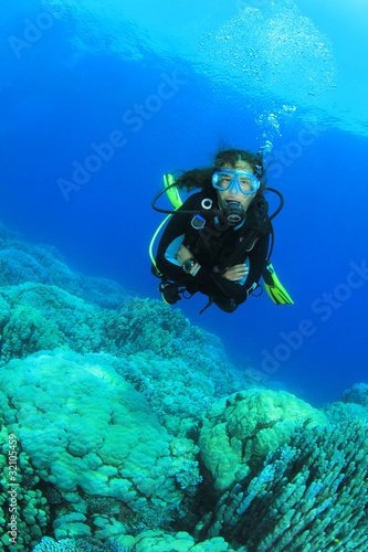 Young Woman Scuba Diving over coral reef