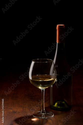 bottle and a glass of wine on a wooden table