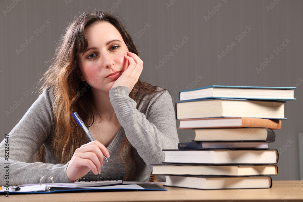 Tired student girl sitting to desk doing homework Tired student girl sitting to desk doing homework